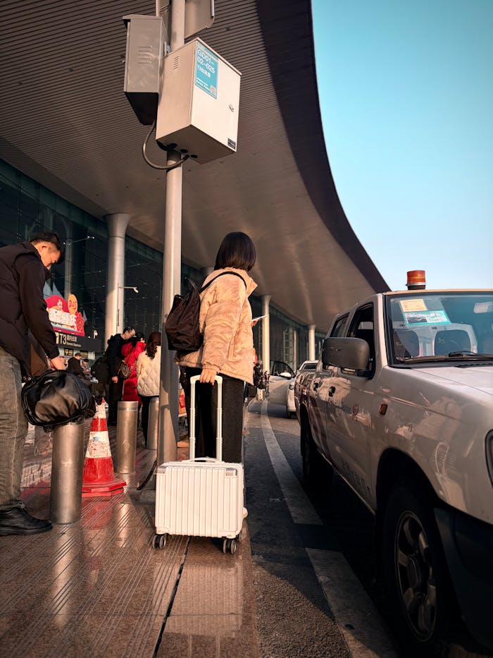 Adult at airport curbside with suitcase, ready to travel. Modern terminal scene.